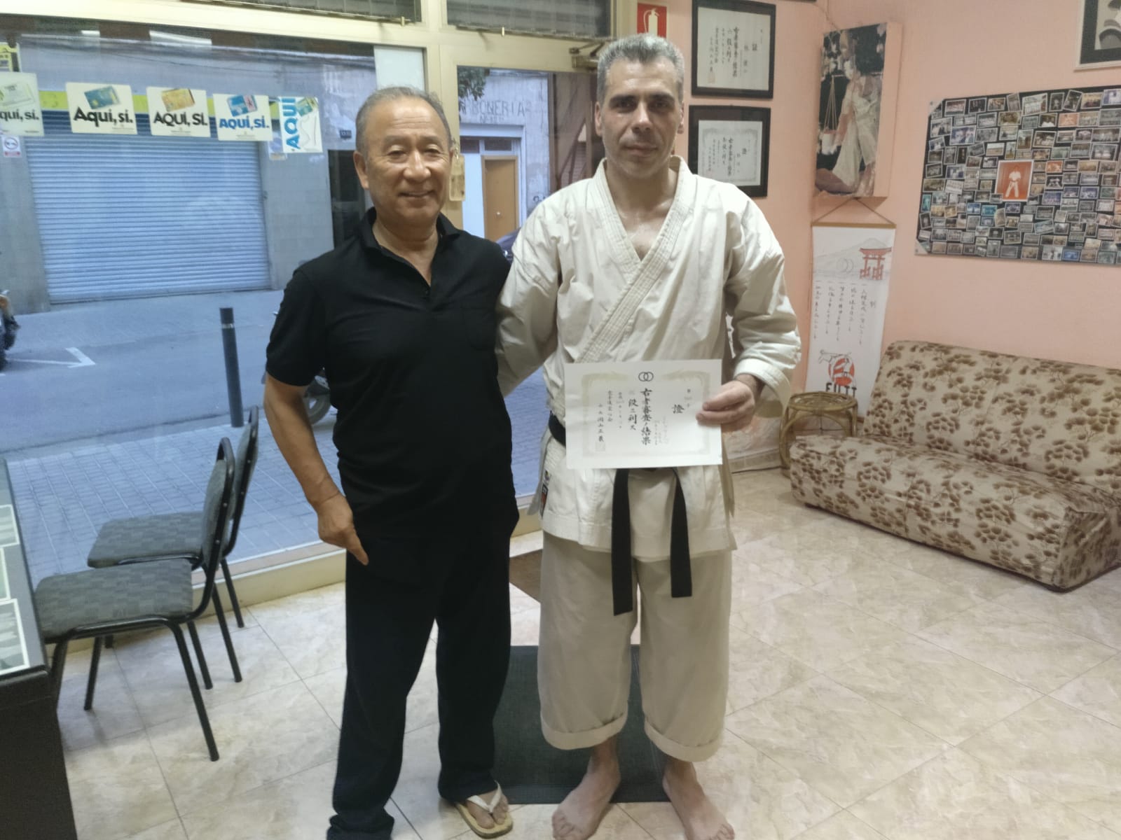 Dos practicantes posan con un diploma; fotografía del archivo de Fudoshin